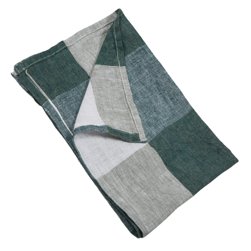 Servilleta de lino doblada, con bloques geométricos en tonos celadon y gris, sobre fondo blanco.