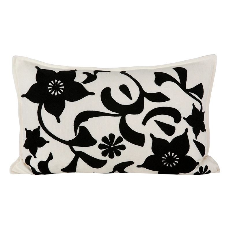Funda de cojín rectangular con bordado floral negro sobre lino crudo, vista frontal.