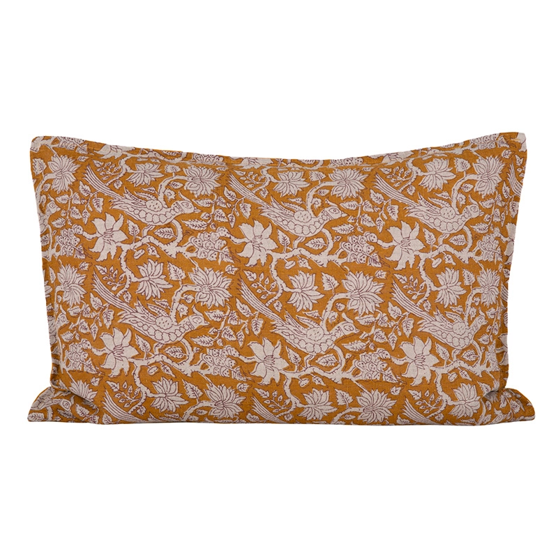 Funda de cojín Jaipur por el frente, con estampado de flores, hojas y aves sobre fondo mostaza.