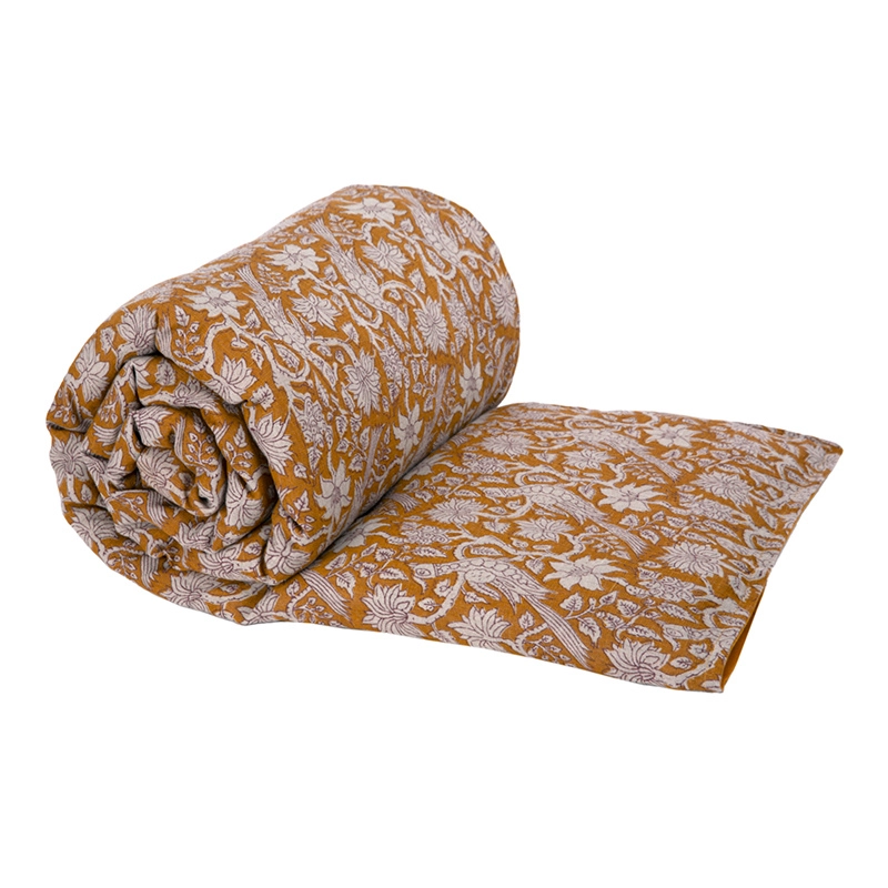 Piecera Jaipur enrollada y extendida, con estampado botánico en tonos claros sobre fondo mostaza.
