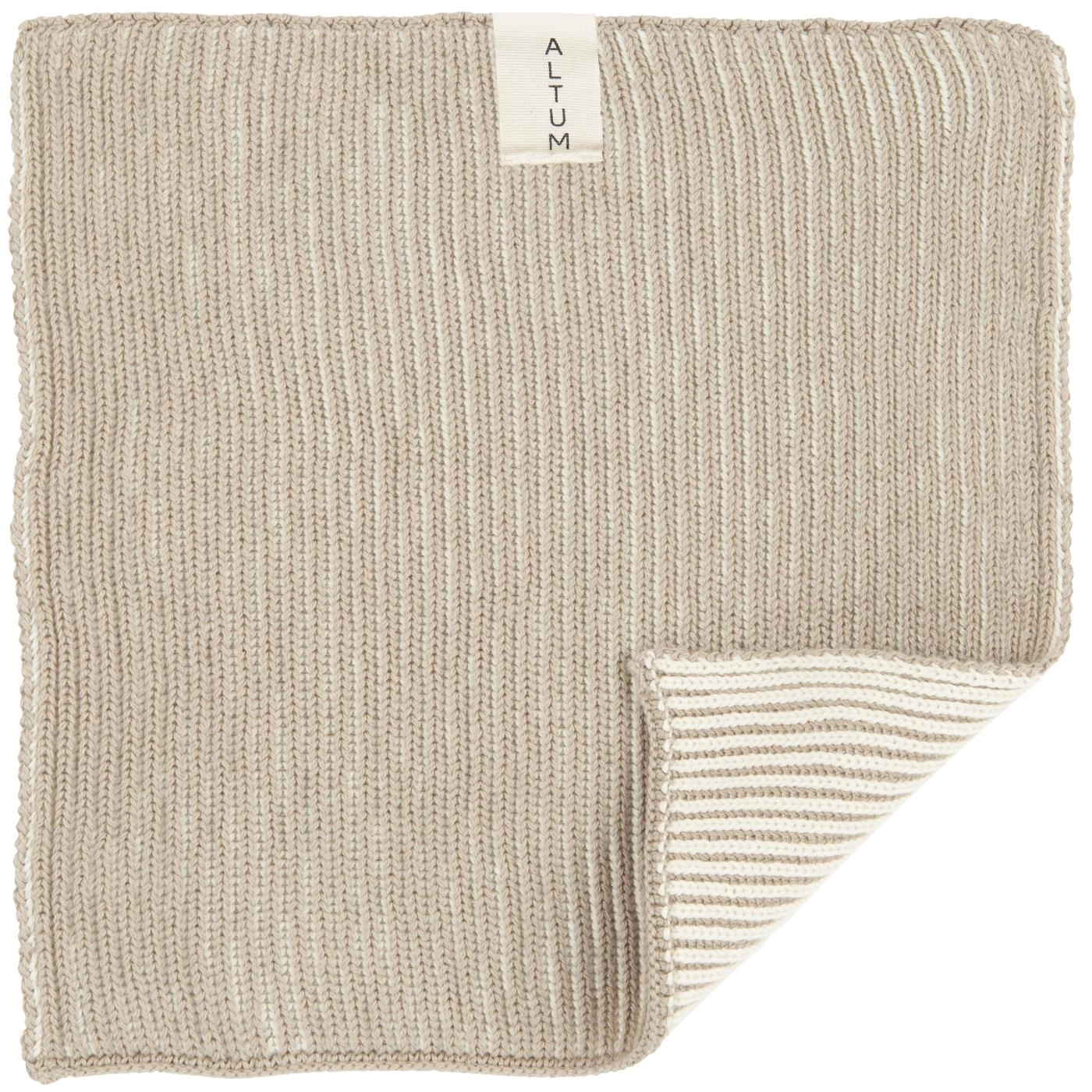 Paño esponja beige extendido, con una esquina doblada que muestra la trama a rayas.