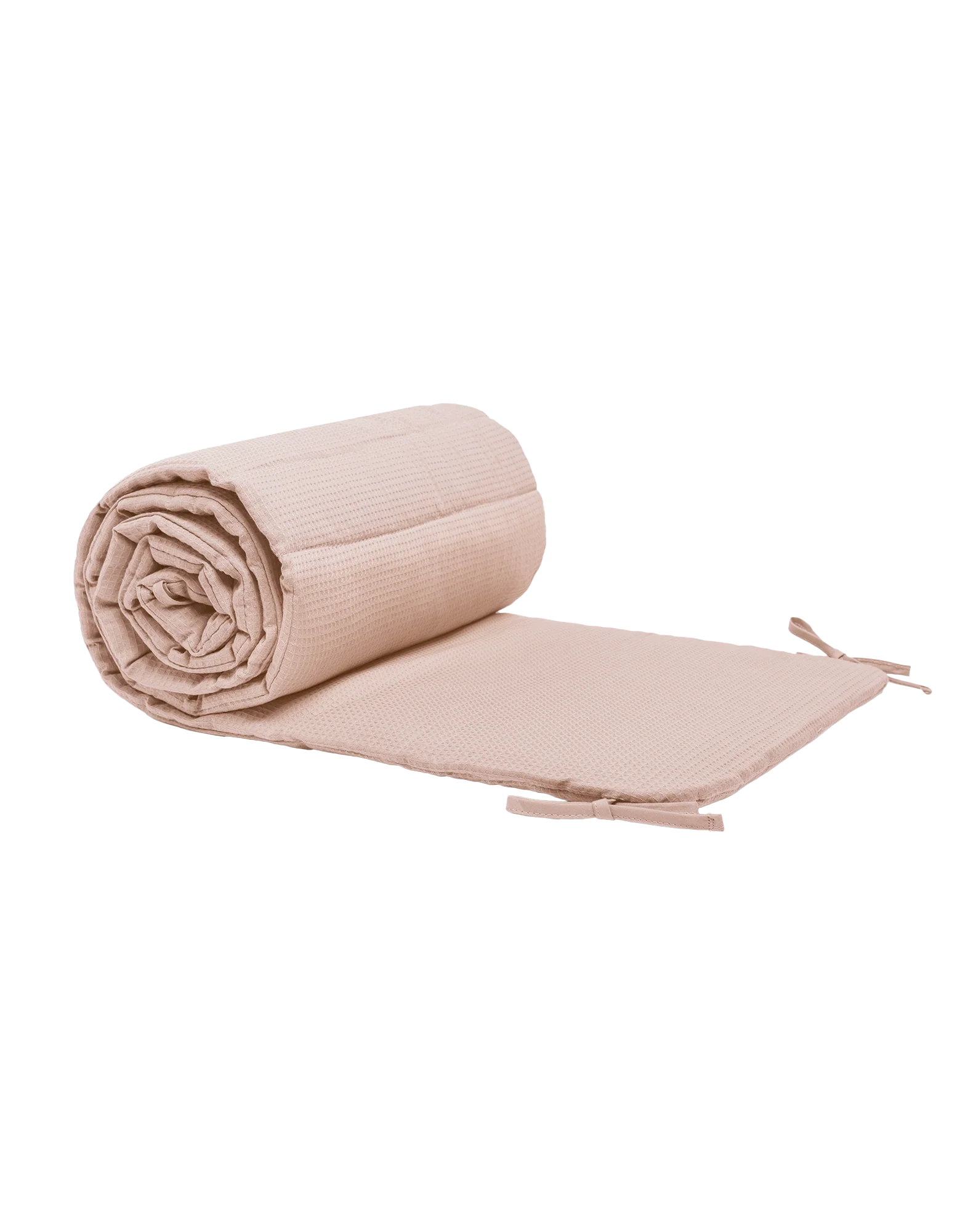 Protector de cuna rosa pálido enrollado junto a un tramo extendido, sobre fondo blanco