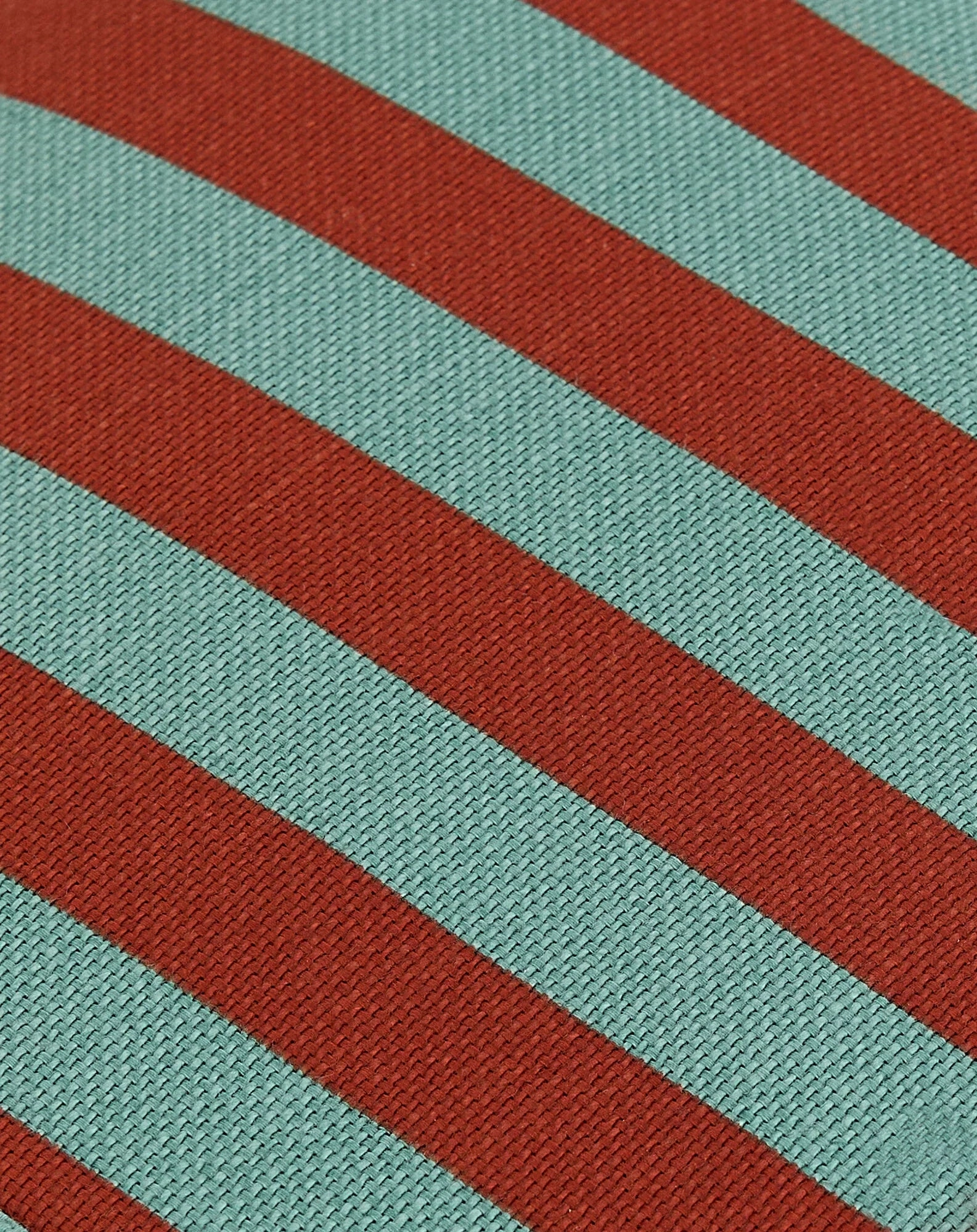 Detalle del tejido del pouf con rayas diagonales rojas y teal.