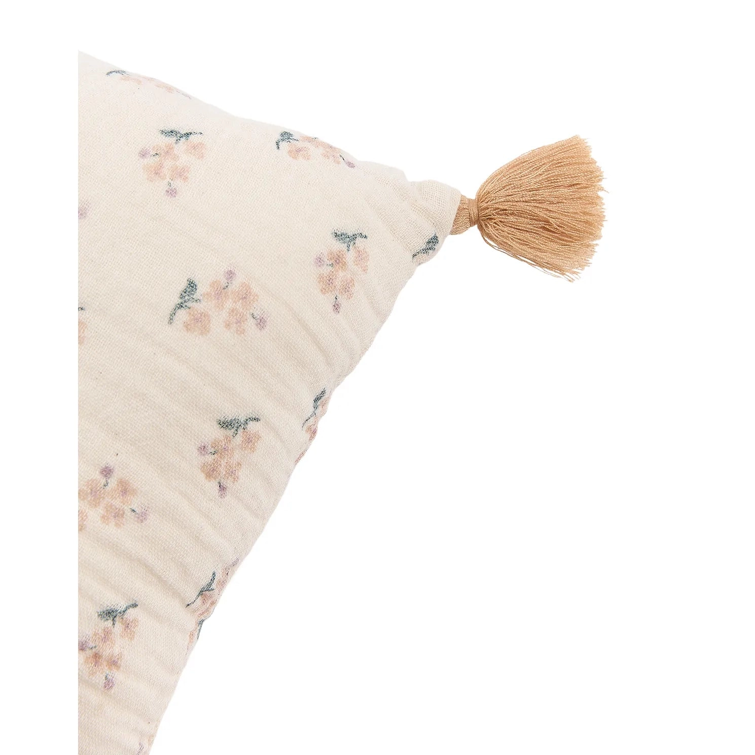 Detalle de una esquina del cojín con estampado floral y pompón, sobre fondo blanco